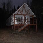 Outside view of cabin set in Maine woods.