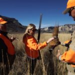 A woman admires a pheasant along with two other bird hunters in Colorado bird country.