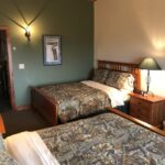 Inside view of a bird hunting lodge bedroom with modern light fixtures and tightly-made beds.