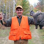 Successful bird hunter holding up ruffed grouse. 