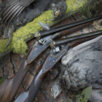 Two open side by side shotguns posed next to harvested dusky grouse.